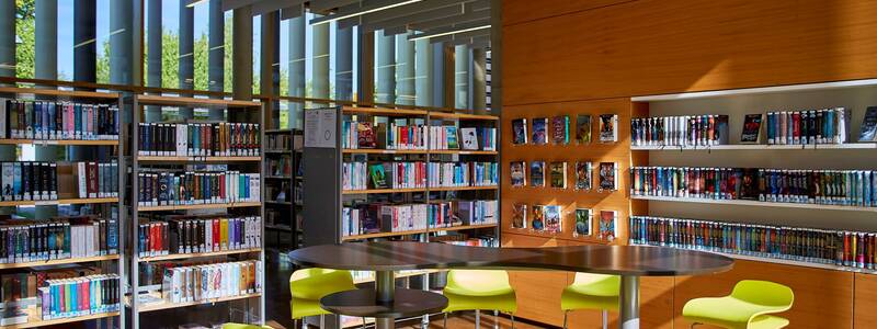 Eine grüne Sitzgruppe im Hintergrund Bücherregale